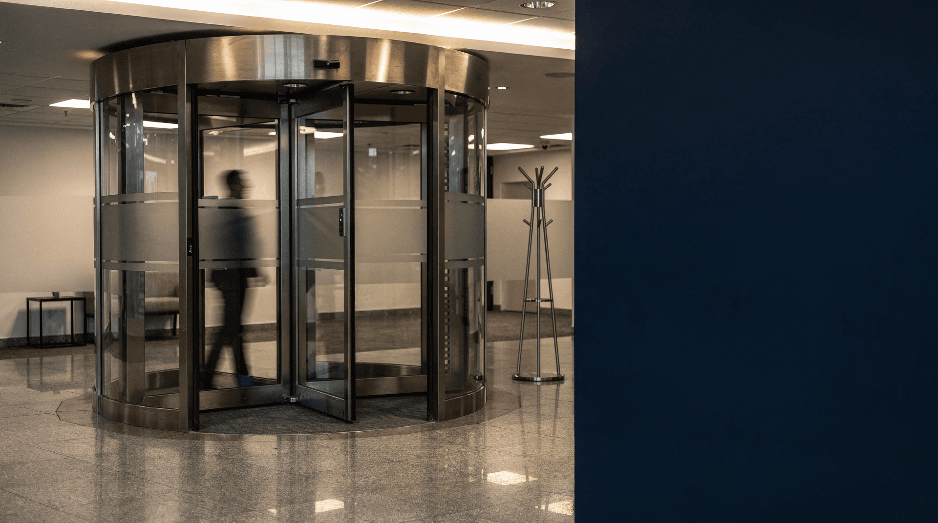 A revolving door in a softly lit office lobby, motion blurred, with empty space beside it