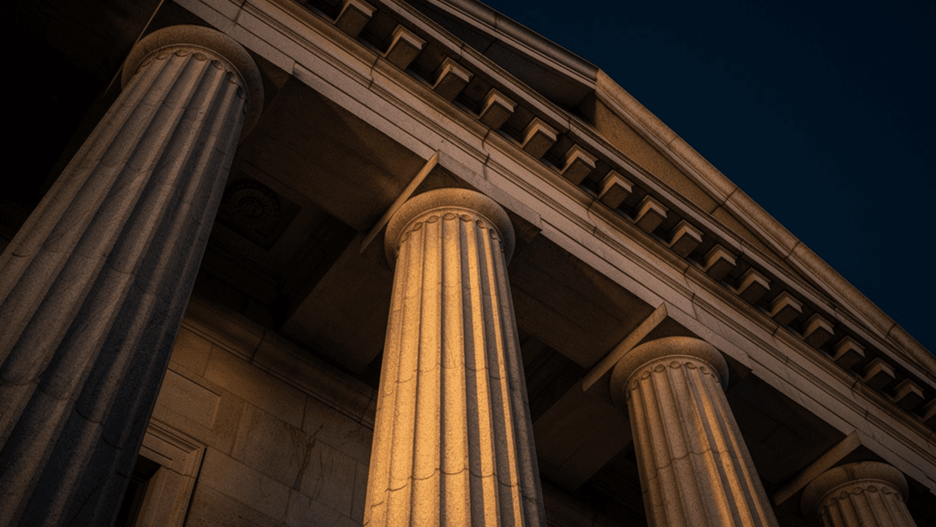 Neoclassical Federal Reserve building facade in dramatic dusk light against a deep navy sky