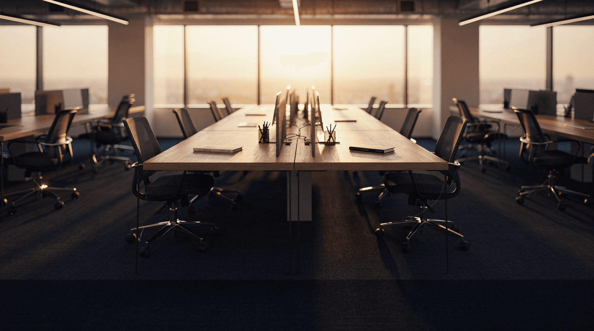 Empty office desks lit by dawn light, evoking a labor market frozen between hiring and layoffs