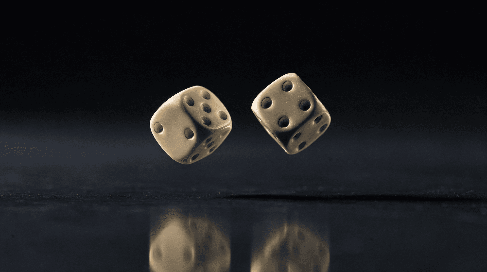 Two ivory dice frozen mid-tumble above a polished dark reflective surface in dramatic light