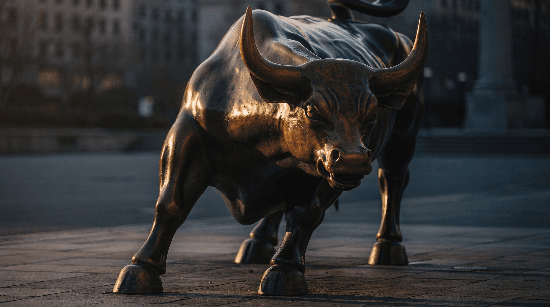 Polished bronze charging-bull statue at golden hour with dramatic side light
