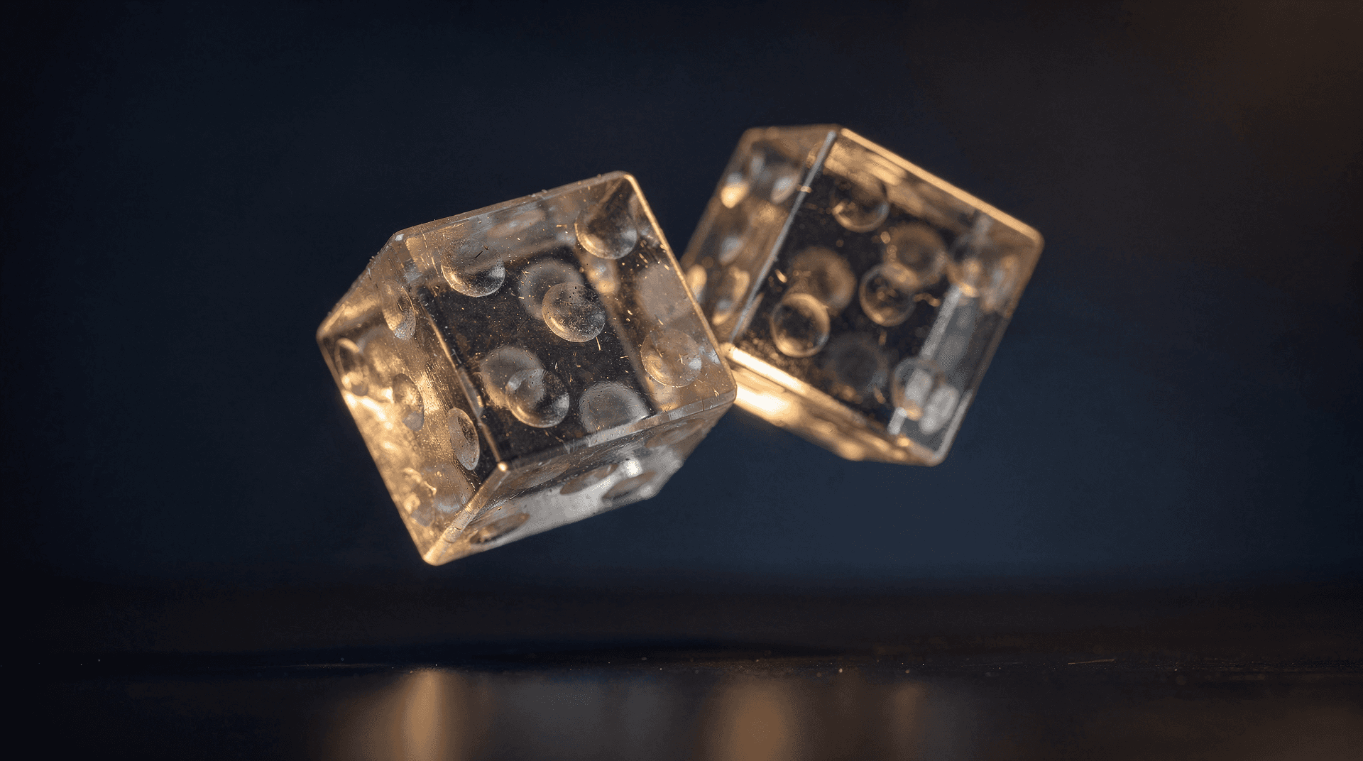 Two translucent dice frozen mid-tumble, silhouetted against a dark navy background with gold rim lighting.