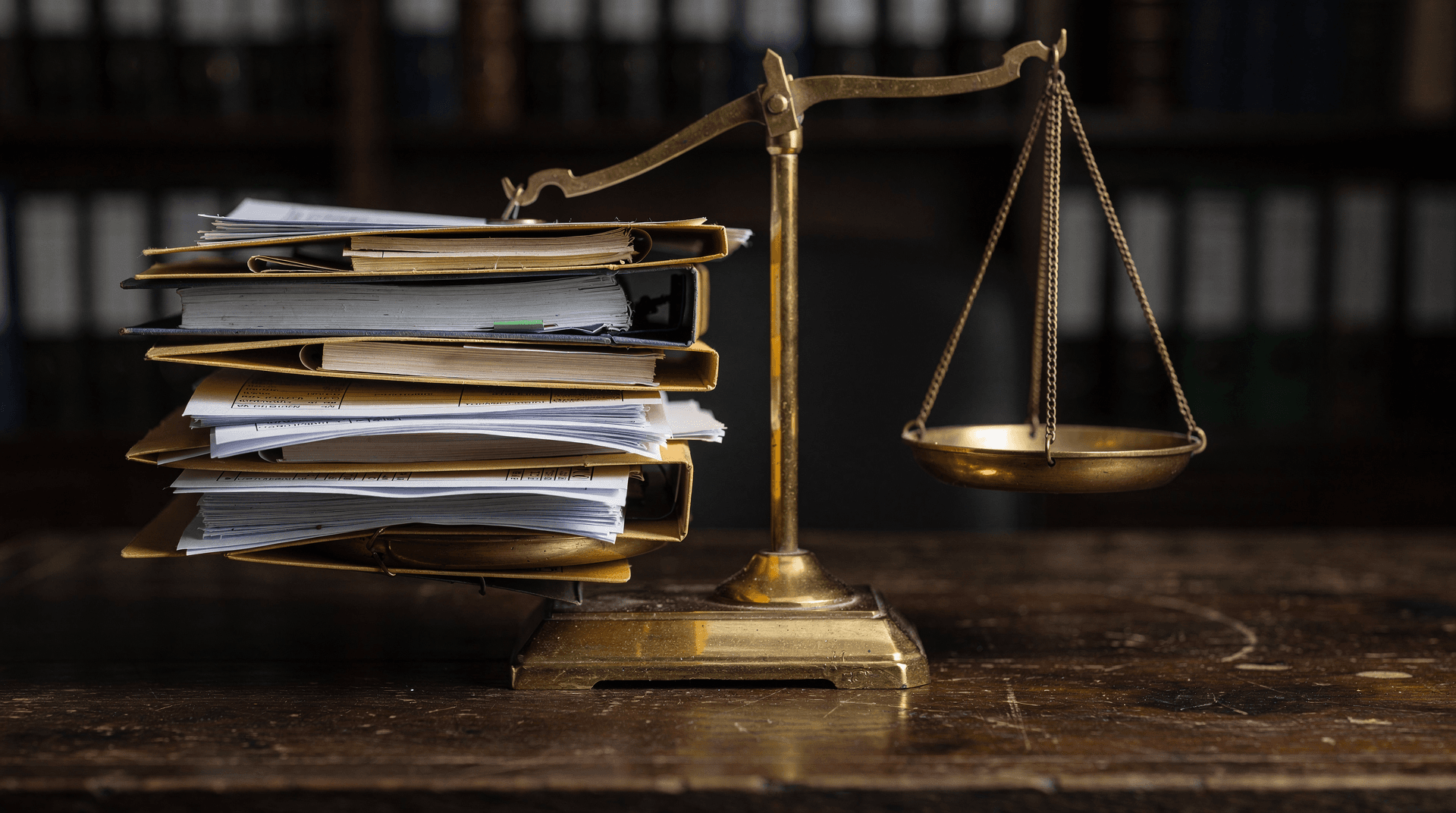 Brass balance scale with one pan weighed down by documents