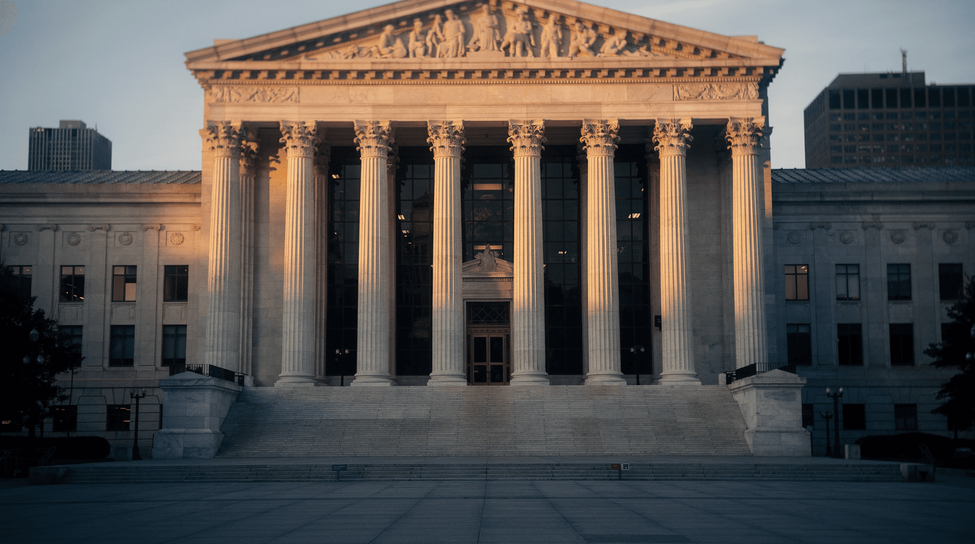 Empty stone government building facade with columns at dawn, soft golden light and deep navy shadows