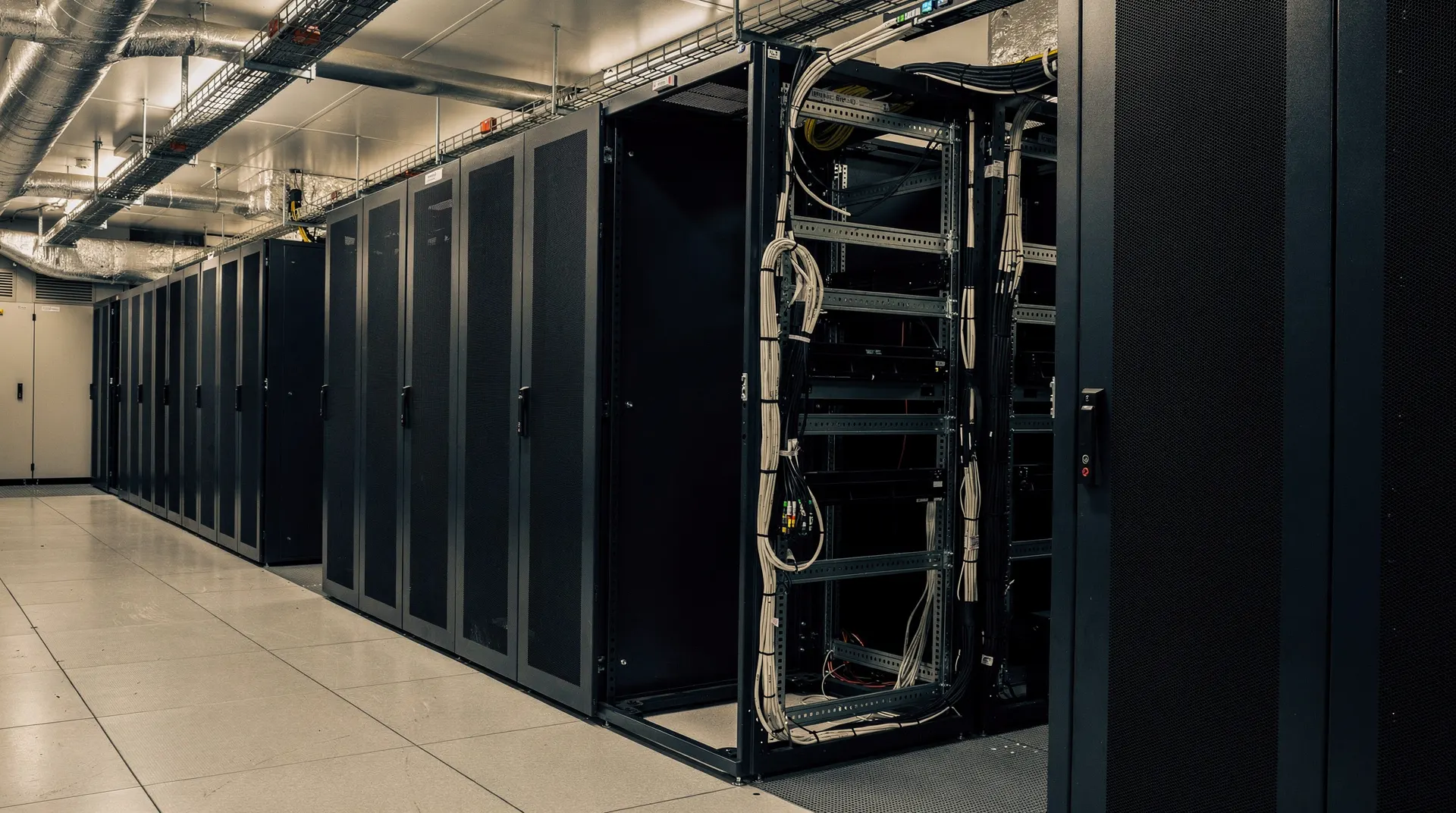 Unmarked server racks recede down a dim data-center aisle beside an unfinished section.