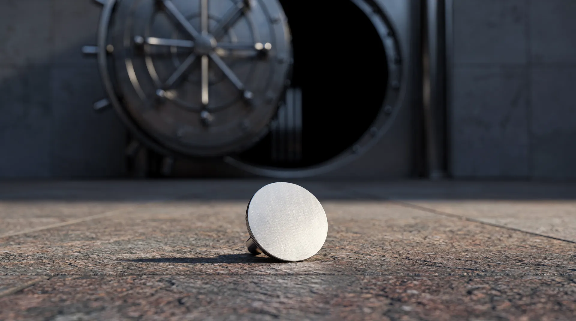 A plain metallic token rests outside an open bank vault door in subdued light.