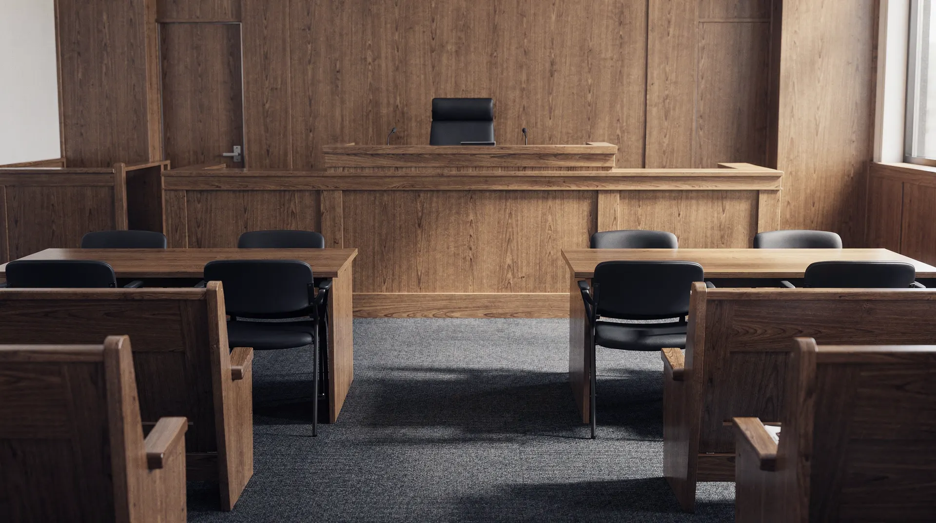 Empty courtroom with opposing counsel tables facing a judge’s bench.