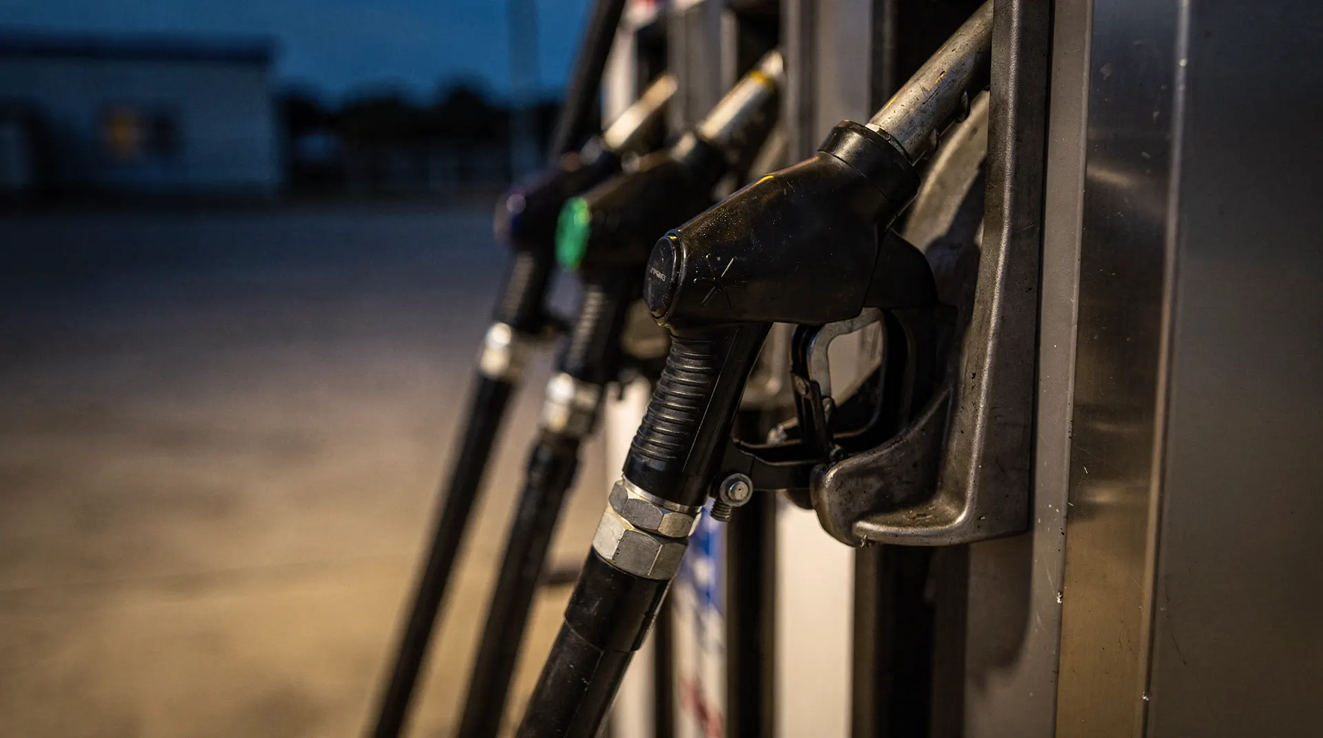 An unmarked diesel fuel-pump nozzle rests against a softly lit, empty forecourt.
