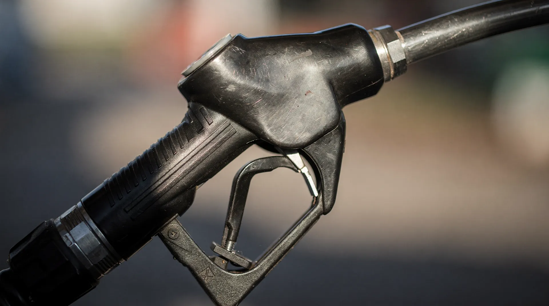 Close-up of a fuel pump nozzle showing brushed metal texture representing consumer inflation
