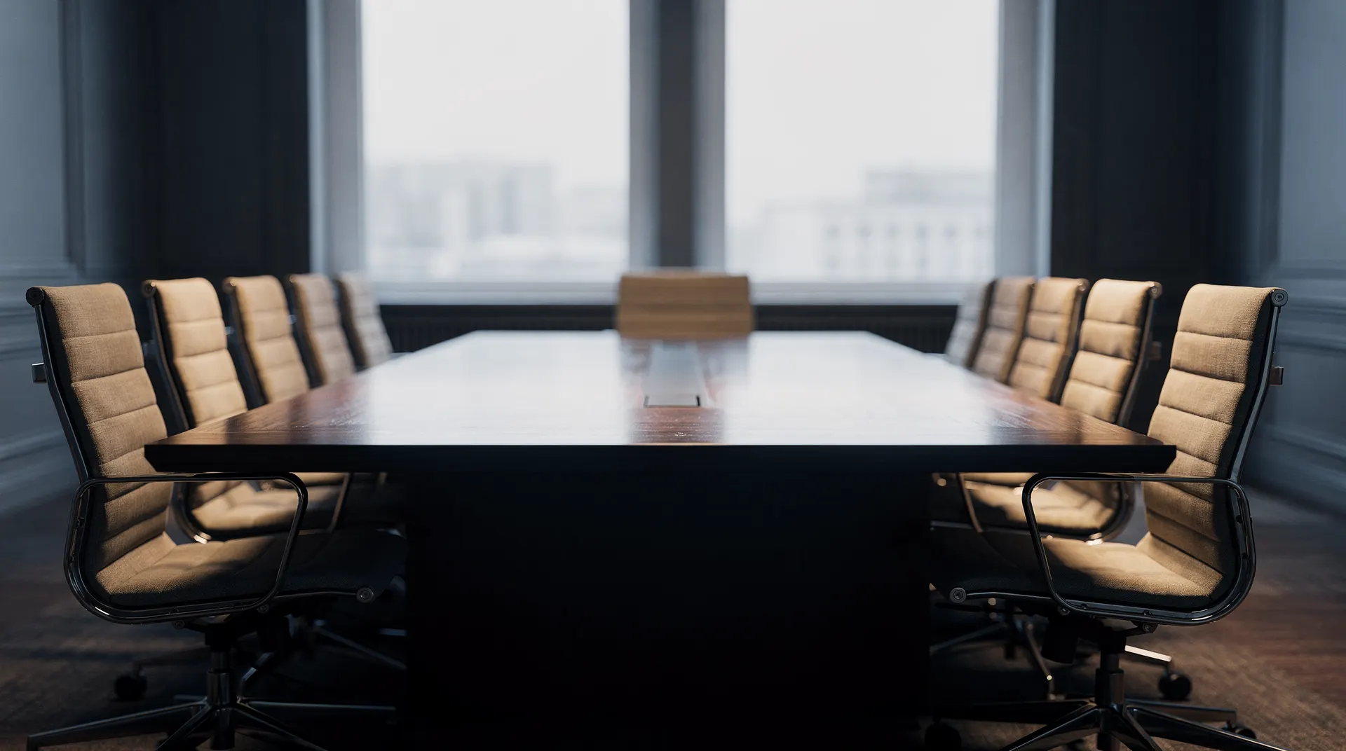 An empty policy meeting room with two chairs angled away from a long conference table.