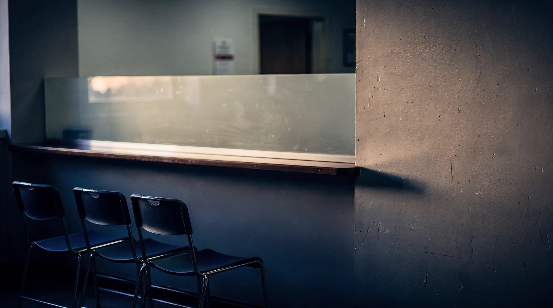 An empty unemployment insurance service counter and waiting chairs in a quiet office.