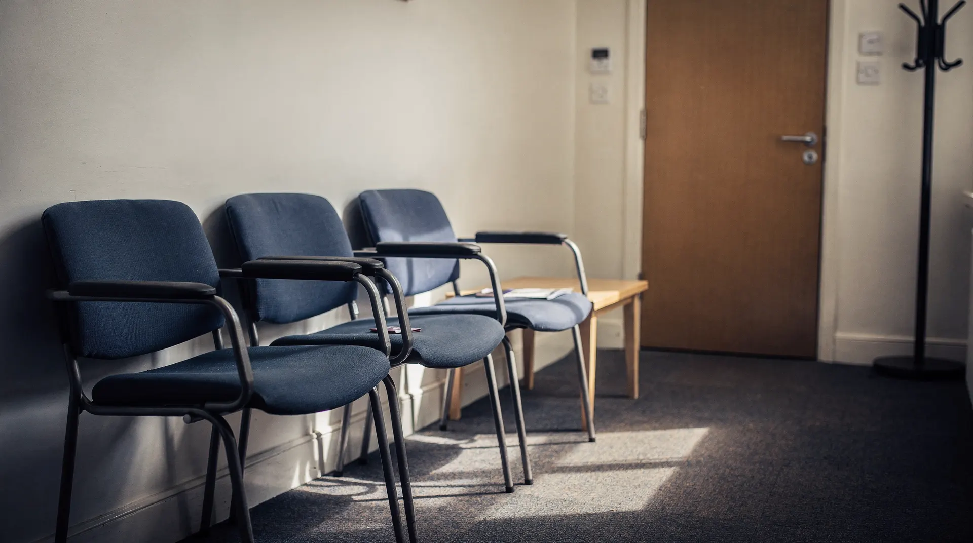 Empty chairs sit in a quiet job center waiting room, with a closed door beyond.