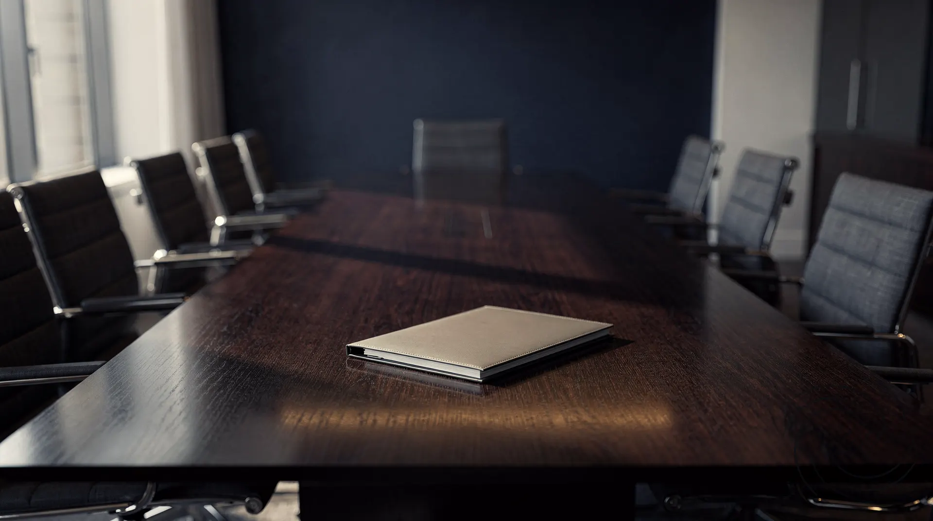 An unmarked folder rests on the table of an empty investment-bank boardroom.