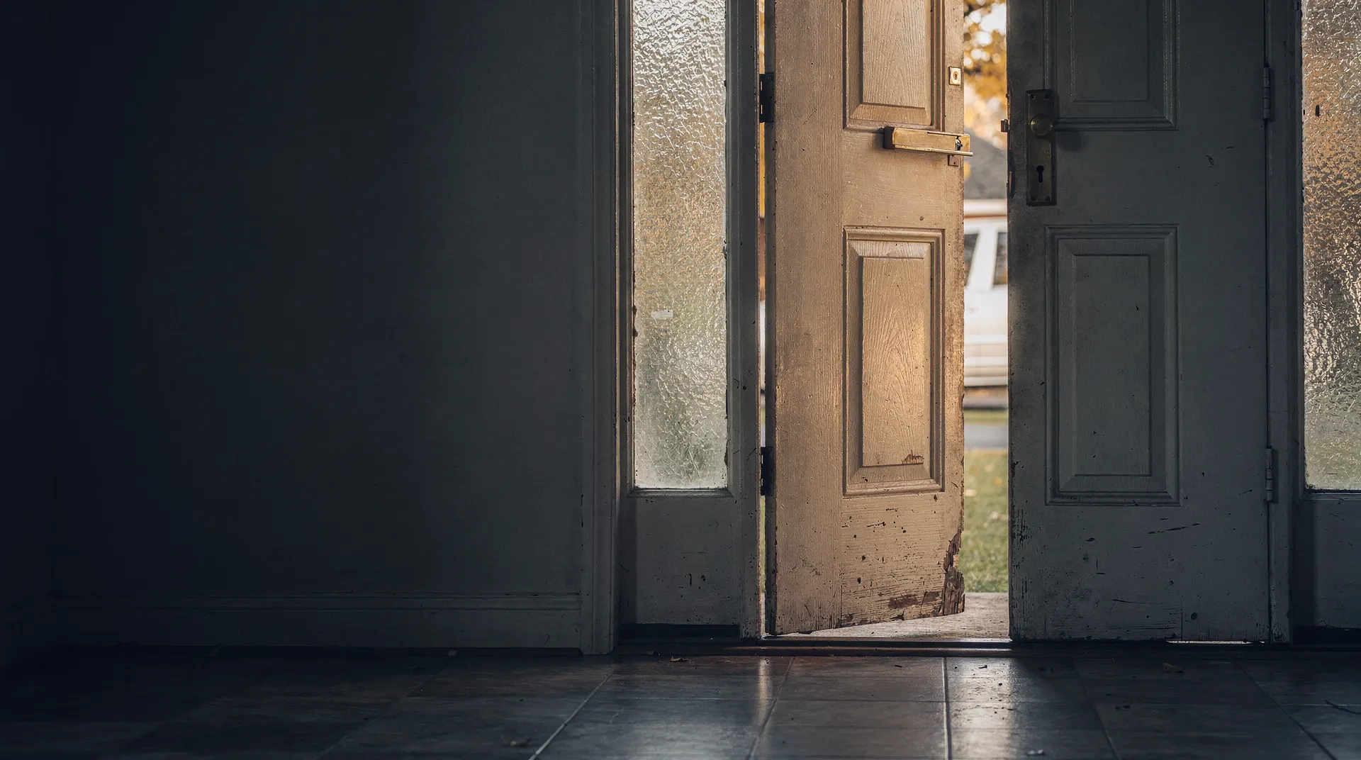 A keyring hangs from the front door of a suburban home in soft autumn light.