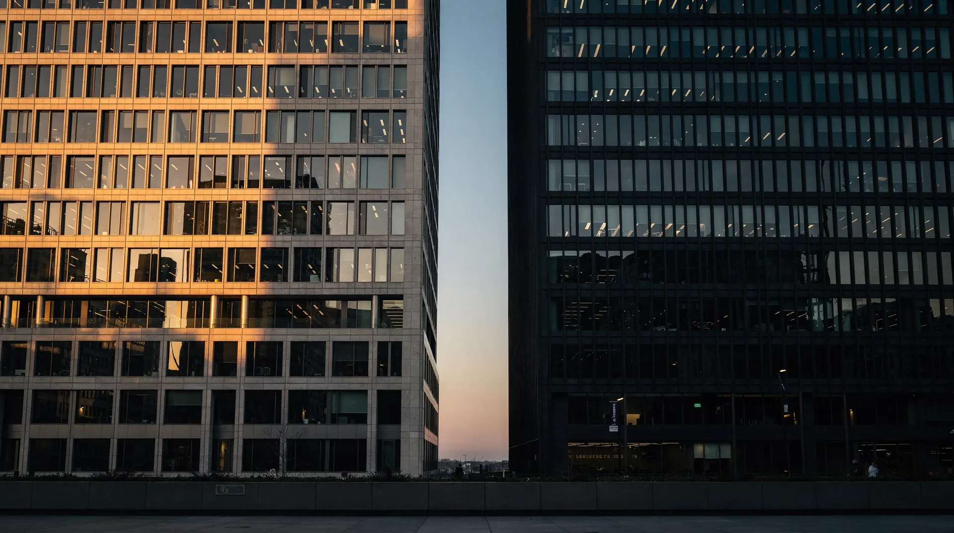 Two bank towers stand side by side, one sunlit and the other in shadow.
