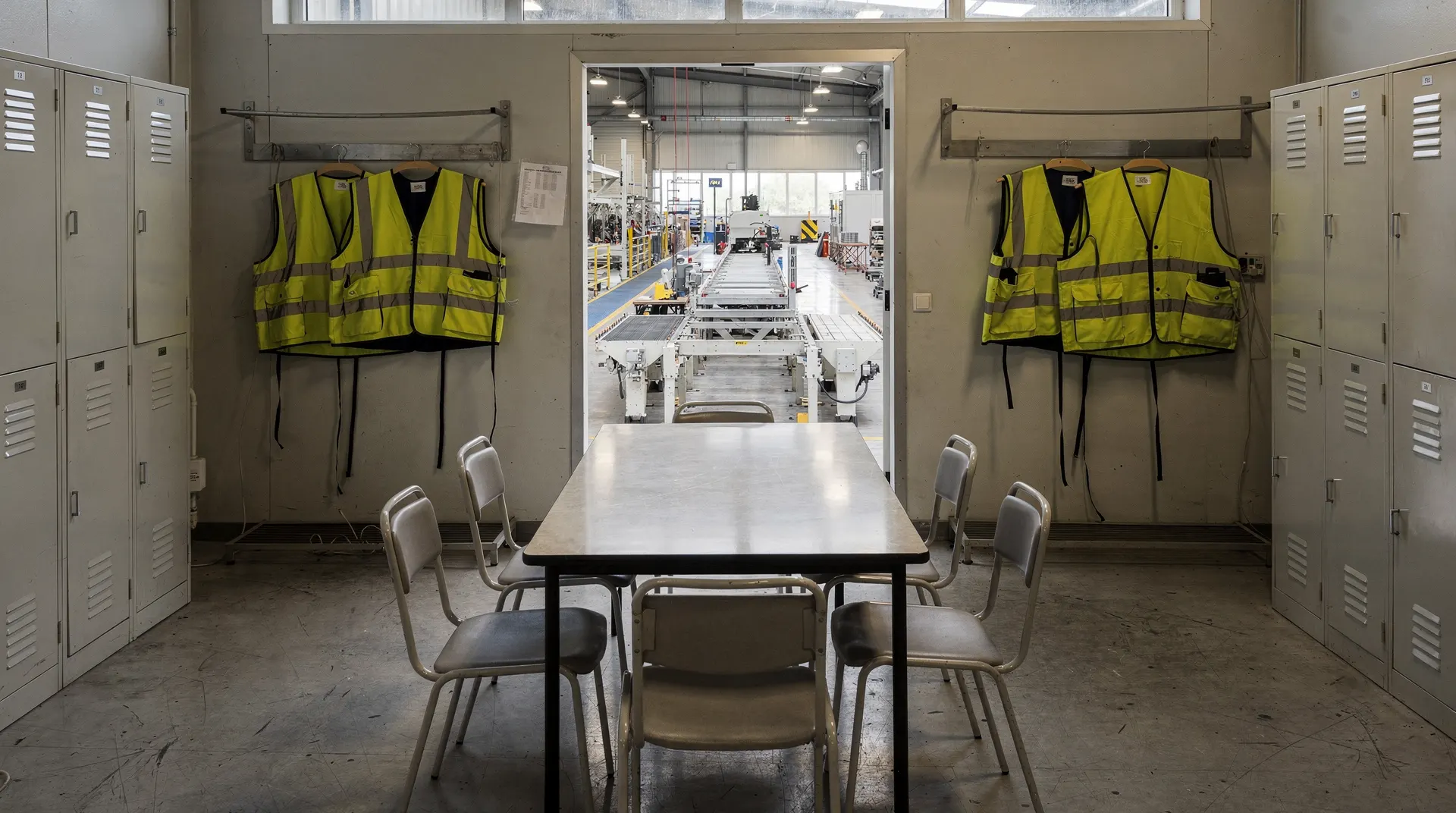 Empty factory break room with chairs, lockers, and a view of the production floor.