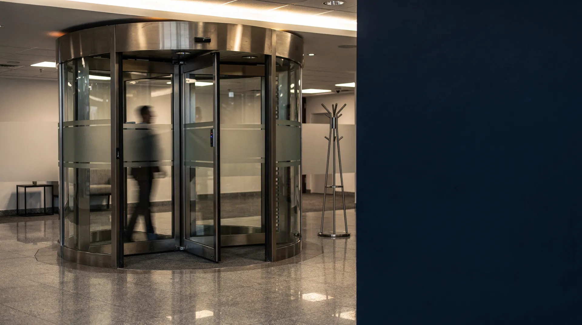 A revolving door in a softly lit office lobby, motion blurred, with empty space beside it