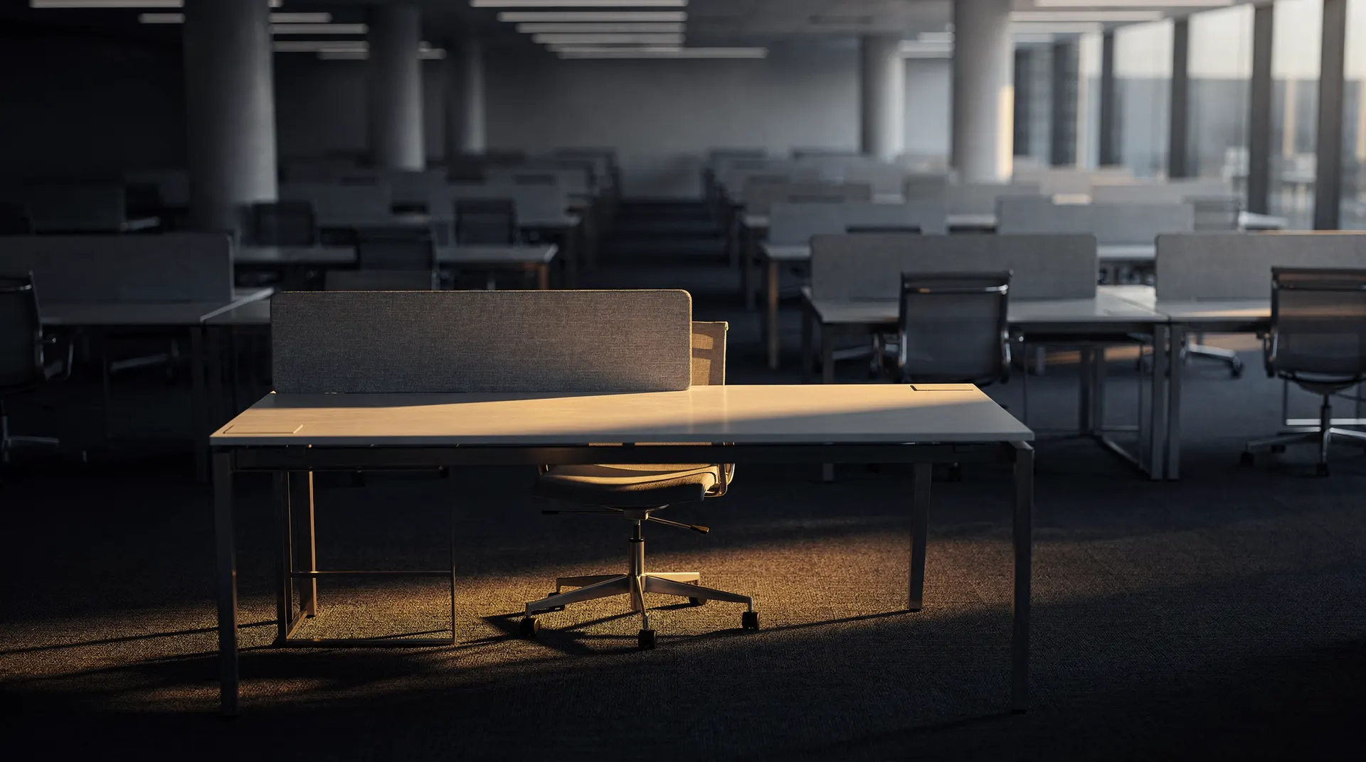 A single lit desk amid the darkness of an empty stock exchange trading floor.