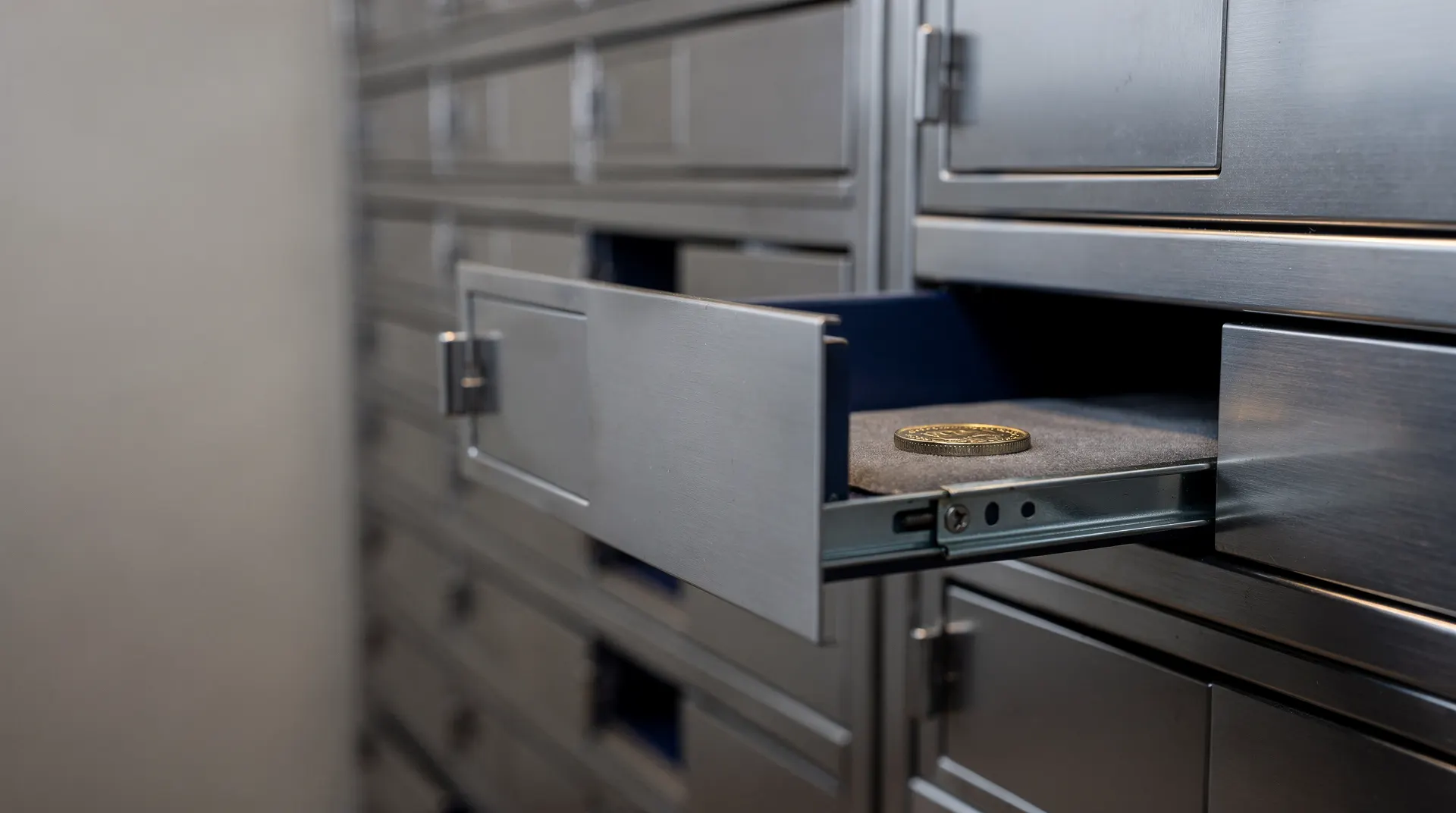A partly open bank vault door reveals a single unmarked metal coin in warm light.